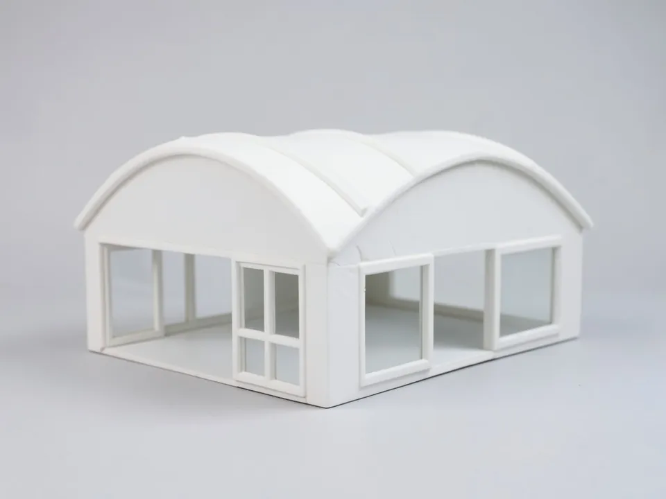 A white clay model of a single-storey house with two side-by-side barrel vault roofs and glazed ends