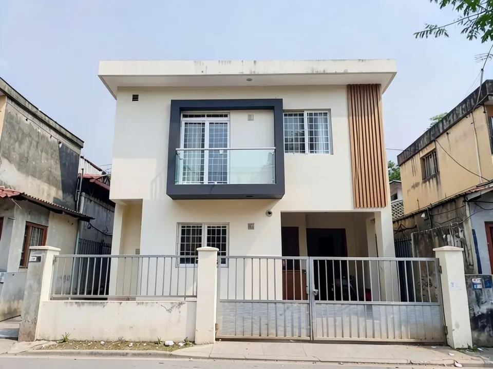 The same house with a dark grey box frame around the first-floor balcony door, a glass balcony railing and a strip of vertical wood louvers on the right of the first floor; gate, boundary wall and neighbours unchanged